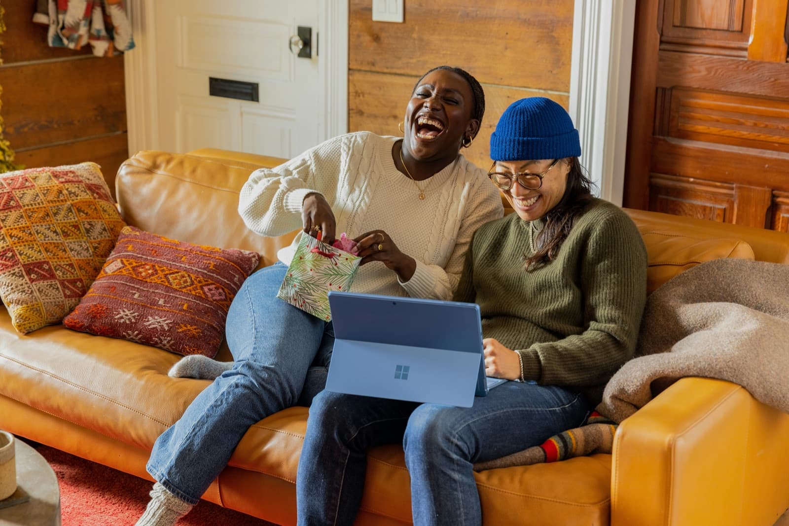 Two people sitting on an orange couch working together on a laptop